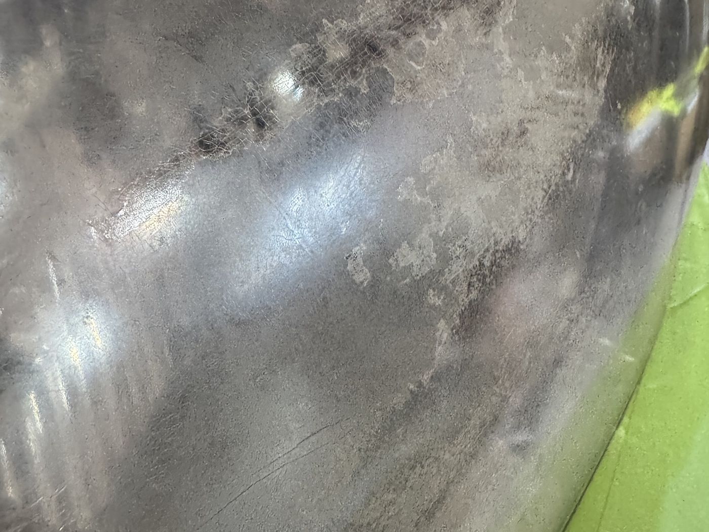 Close-up of a headlight lens before restoration: flaking, crazed factory coating